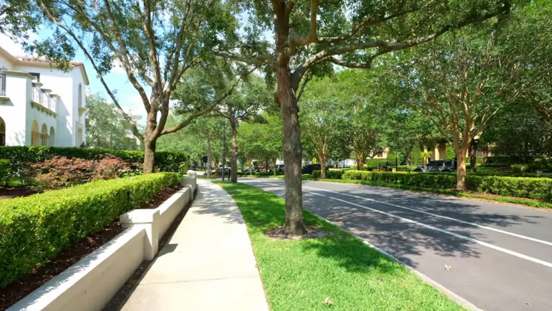 Tree-lined sidewalk and quiet street in Baldwin Park, Orlando, surrounded by greenery and well-kept residential buildings