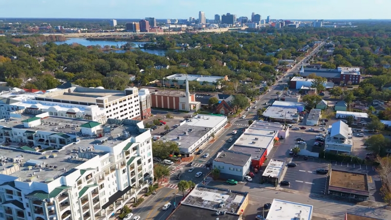 Aerial view of College Park in Orlando with tree-lined streets, low-rise buildings, and downtown skyline in the distance