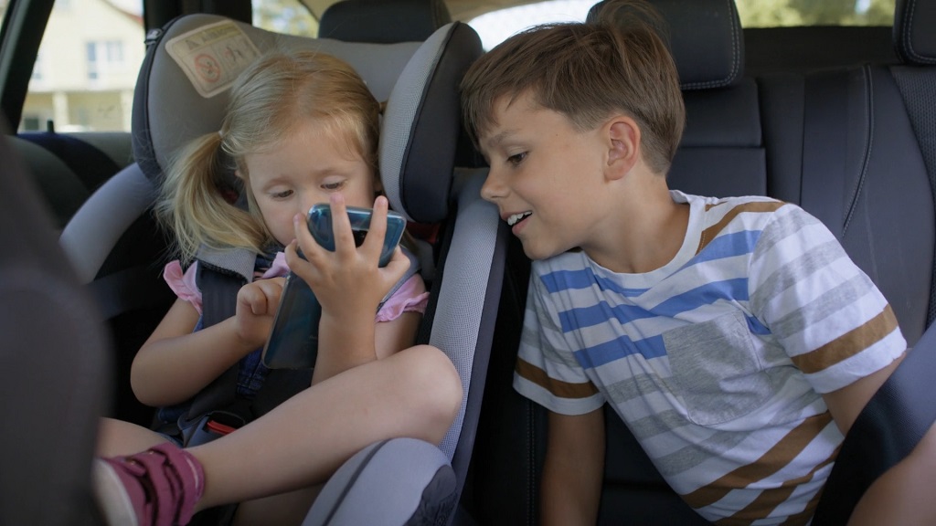 Kids in the backseat enjoying entertainment during a long drive