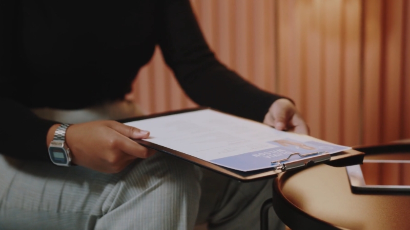 A person holds a clipboard with school admission forms during a private school application meeting