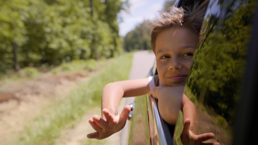 Kid enjoying the ride on a road trip from Florida to Missouri, leaning out the car window