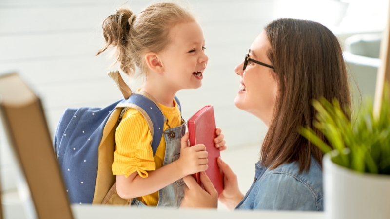 A smiling parent and child share a moment after summer camp drop-off in Orlando