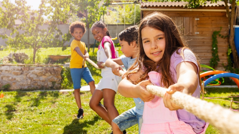 Kids play tug-of-war outside at summer camp in Orlando, enjoying teamwork and outdoor fun in a safe, supervised setting